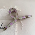 Close-up of grey and purple leopard print hair claw clip on beige linen fabric - Crossed