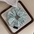 Close-up of mint green sequin scrunchie with silver sparkles on a wooden display tray - Mint Green
