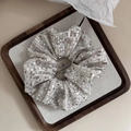 Macro detail of sparkling silver sequin scrunchie with shiny texture and elastic band - Champagne