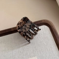 Detailed macro shot of elegant leopard print hair claw clip on a stylish wooden tray - Leopard Print