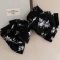 Detalle de un lazo grande negro para el cabello con patrones de rosas blancas y estampado - Estilo Negro con Flores Pequeñas
