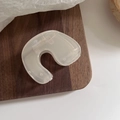 Detail view of a translucent matte U-shaped hair claw clip on a dark walnut wood tray - N Shape Style / Jelly White - N Shape