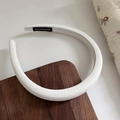 Detalle de la diadema acolchada blanca con etiqueta artesanal sobre fondo de madera - Blanco