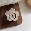 Détail d'une pince à cheveux camélia blanc crème translucide posée sur un support en bois - Blanc Gelée - Camélia