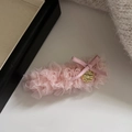 Dettaglio del fermaglio in pizzo rosa con fiocco dorato e targhetta in metallo lucido - Rosa