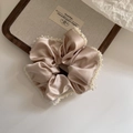 Dettaglio dello scrunchie in raso champagne con bordo di perle per acconciature - Albicocca