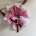 Close-up of a plaid floral scrunchie with lace trim, ribbon bow, and white faux pearl detail - Red