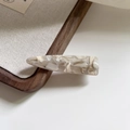 Detailed macro view of handmade cream and brown marble acetate hair clip texture - Cream White
