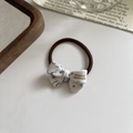 Detail of a handmade marble acetate bow hair tie with a gold-tone luxury brand logo - Gray White