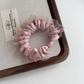 Détail d'un chouchou en satin rose avec bords en dentelle sur plateau en bois - Rose
