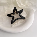 Detailed close-up of a star-shaped black hair claw clip with golden metal spring - Black