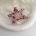 Close-up of a hollow star hair claw with purple marble pattern on a white tray - Purple Floral Pattern