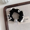 Dettaglio scrunchie nero con pizzo bianco e perla cangiante su vassoio in legno - Stile Perla - Nero