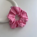 Macro detail of a pink fabric scrunchie on white ceramic plate with a brand woven label - Pink