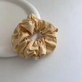 Detailed view of yellow fabric scrunchie with soft pleats on a white ceramic plate - Yellow