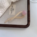 Dettaglio macro di un fermaglio per capelli in acetato crema con perla rosa marmorizzata - crema