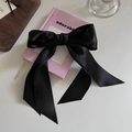 Elegant black satin bow hair clip with long ribbons on a pink decorative book - Black