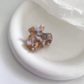 Detail view of mini acetate hair claw with brown marble pattern and gold text lettering - Camellia