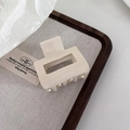 Minimalistische cremefarbene Haarklammer in Rechteckform auf elegantem Holztablett - Cremeweiß