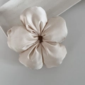 Détail d'un grand chouchou fleur en satin champagne avec des pétales rembourrés - Abricot