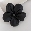 Détail d'un chouchou fleur en satin noir sur un plateau de présentation minimaliste - Noir