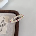 Close-up of small oval hair clip with colorful polka dots and golden metal clip - White Hollow Oval Hair Clip