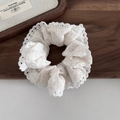 Detailed view of cream lace scrunchie with blue polka dots on a vintage wooden tray - Green