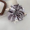 Dettaglio dell'elastico in raso metallizzato viola con fiocchi intrecciati panna - Argento