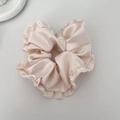 Close-up detail of champagne satin ruffled scrunchie with soft metallic silk texture - Apricot