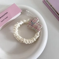 Detail eines süßen Kaninchen-Haargummis mit buntem Karomuster und weißem Faltenstoff - Kariert Hase Haargummi