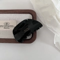 Macro shot of black acetate shark clip with golden Barrette La France text on wood tray - Black