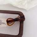 Close-up of tortoise shell pattern acetate bow hair clip on a minimalist wooden tray - Coffee/Brown