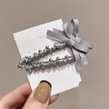 Détail d'une pince à cheveux perlée argentée avec un nœud en tissu gris sur carte - Clips BB