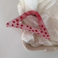 Pink triangle hair claw with red polka dots in a white tray on crumpled paper background - Pink Triangle