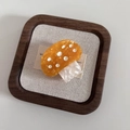 Dettaglio macro di un fermaglio per capelli a fungo in acetato arancione a pois bianchi - Giallo