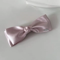 Detalle de la pinza de lazo de satén rosa con una pequeña placa metálica plateada - Rosa