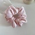 Gros plan d'un chouchou en tissu jacquard rose clair avec des motifs de grille fins - Rose