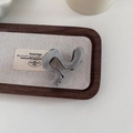 Detail einer grauen S-förmigen Haarklammer aus Acetat auf einem Holztablett - Grau