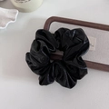 Makroaufnahme eines großen schwarzen Scrunchies mit glänzender Lederstruktur und Falten - Schwarz Groß