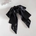 Detalle de pinza para el cabello con lazo de satén negro y estampado de hojas de bambú - Rama de bambú