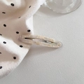 Detailed macro view of hollow oval acetate hair clip with marble texture and metal spring - Creamy White Marble