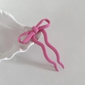 Dettaglio di un fermaglio per capelli rosa con fiocco e rebbi ondulati su piatto ceramico - 4# Rosa