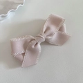 Detalle de un pasador de pelo con lazo rosa empolvado con bordes rizados y textura fina - Estilo Albaricoque