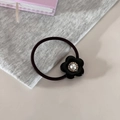 Detalle de un coletero negro con una flor de perla vintage sobre un escritorio - Negro
