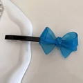 Detail of royal blue acrylic bow hair clip with gold handmade text on white tray - Blue