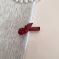 Dettaglio del fermaglio a fiocco rosso scuro con scritta dorata France Handmade in metallo - Rosso