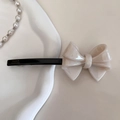 Close-up of handmade cream bow hair clip with gold France engraving on black base - Off-white