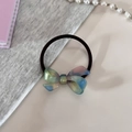 Detailaufnahme eines irisierenden Acetat-Bogen-Haargummis mit schwarzem Gummiband auf Stoff - Aurora