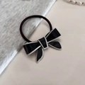 Detail view of a black acetate bow hair tie with cream piping on a soft knit background - Black Hair Tie