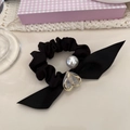 Dettaglio scrunchie in raso nero con perla grigia, ciondolo cuore e fiocco in seta - Cuore